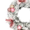 Zasnežený adventný veniec s ružovými vianočnými guľami a ružovými mašľami. Detail
